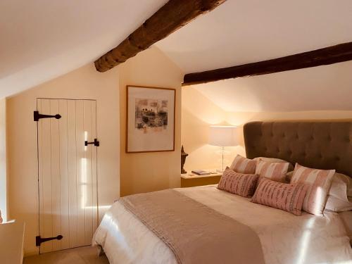 een slaapkamer met een groot bed met roze kussens bij Vine Cottage in Chipping Campden