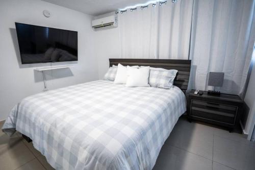 a bedroom with a bed with a checkered blanket and a television at Aquaville Dorado Moderna Villa 1 in Dorado