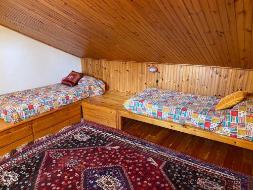 ロッカ・ディ・メッツォにあるCasa di montagna nel borgo di Rocca di Mezzoのベッド2台とラグが備わる客室です。