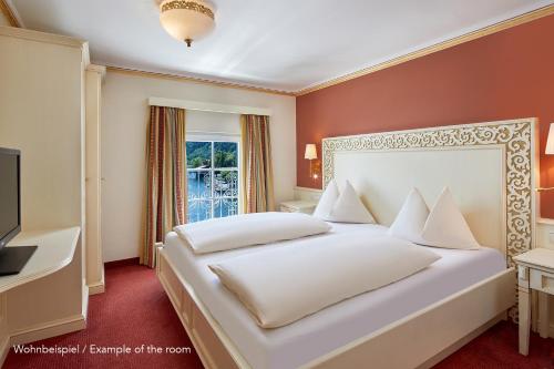 a bedroom with a white bed and a window at Grand Hotel Zell am See in Zell am See