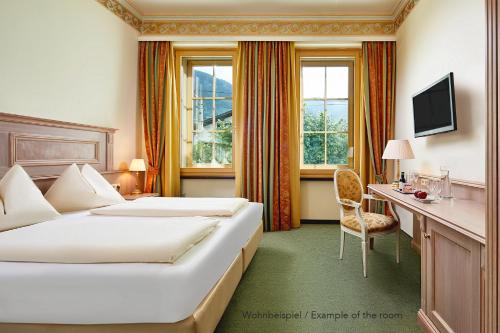 a hotel room with two beds and a desk at Grand Hotel Zell am See in Zell am See