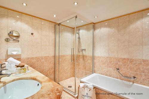 a bathroom with a shower and a sink and a tub at Grand Hotel Zell am See in Zell am See