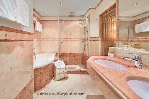 a bathroom with a sink and a tub and a shower at Grand Hotel Zell am See in Zell am See