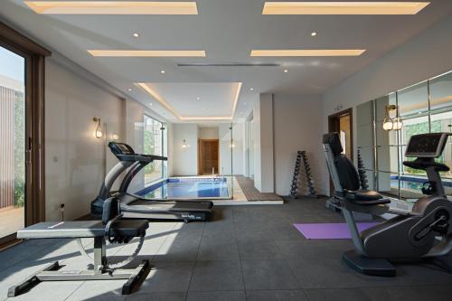 a gym with cardio machines and a swimming pool at Gladiolus Hotel in Jeddah