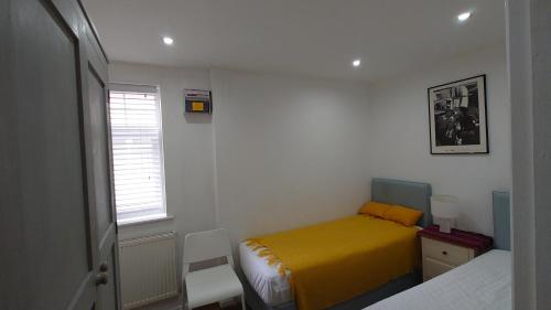 Molesey near Hampton Court, Viking Short Stays في West Molesey: غرفة نوم صغيرة بسرير اصفر ونافذة