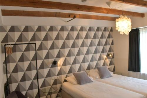 a bedroom with two beds and a checkered wall at Hotel Steeds aan Zee in Katwijk
