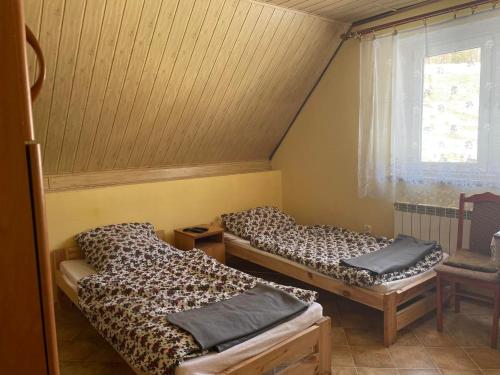 a room with two beds and a window at agroturystyka Pensjonat PAULA in Muszyna