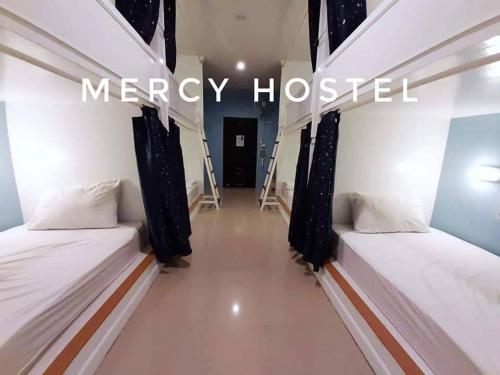 twee bedden in een kamer met de woorden Mercy ziekenhuis bij Mercy Hostel in Chiang Rai