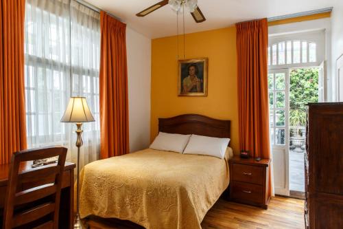 a bedroom with a bed with orange curtains and a window at Hotel Casa Gonzalez in Mexico City