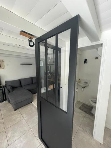 - une porte noire dans le salon avec un canapé dans l'établissement Maisonnette, à Sainte-Soulle