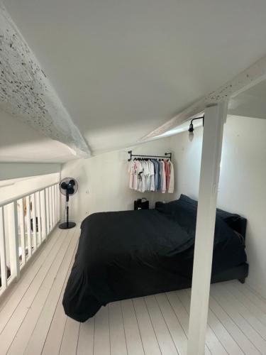 1 dormitorio con cama negra y balcón en Maisonnette en Sainte-Soulle