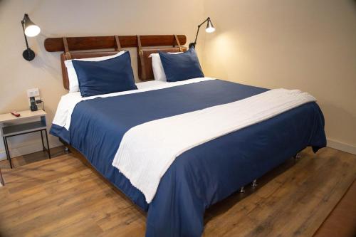 uma cama grande com lençóis azuis e brancos e almofadas azuis em Grace Chapinero em Bogotá
