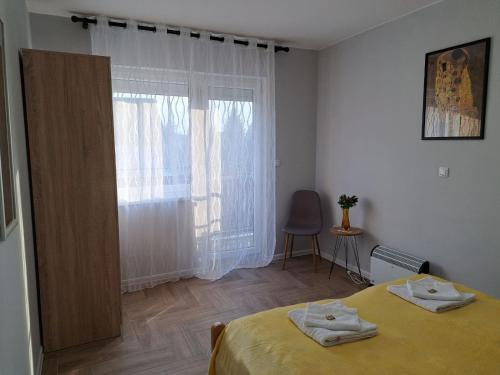 a bedroom with a yellow bed and a window at Apartments Manna Palic in Palić