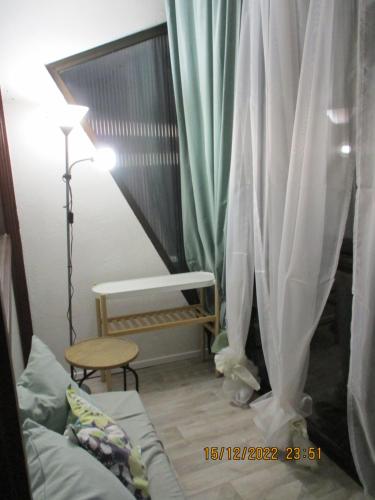 Cette chambre comprend un canapé, une lampe et des rideaux. dans l'établissement Studio dans la station de ski La Bresse-Hohneck, à La Bresse