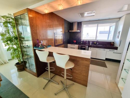 a kitchen with a white counter and stools at Apartamento espetacular, melhor vista e localização de Torres in Torres