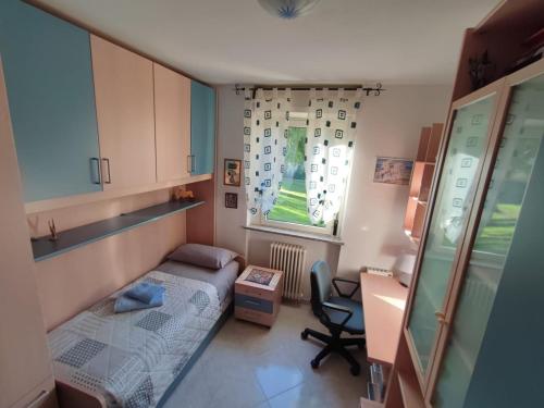Habitación pequeña con cama, escritorio y ventana en Singola in famiglia (MyAostaProject - Rentals) en Aosta