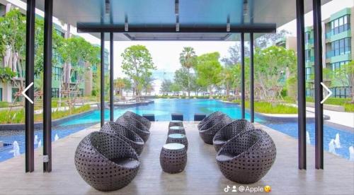 a row of bean bags sitting in front of a pool at Apple Beach ChaAum in Cha Am