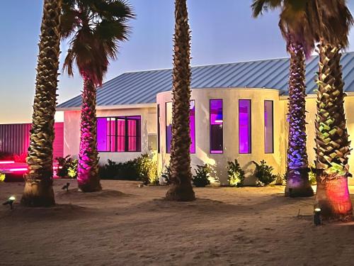 a building with palm trees in front of it with purple lights at The Castle House Estate in Joshua Tree