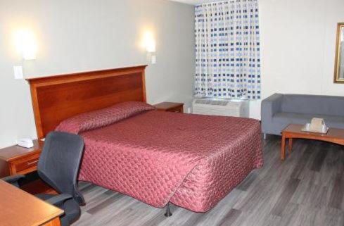 a hotel room with a red bed and a chair at Araamada Inn in Albany