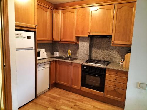 a kitchen with wooden cabinets and a white refrigerator at Apartamento en Esterri Visita Aiguestortes in Esterri d'Àneu