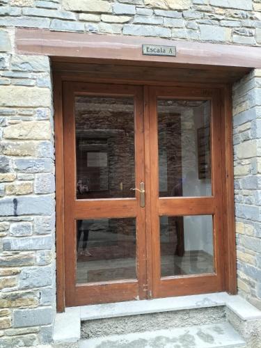 a wooden double door in a stone building at Apartamento en Esterri Visita Aiguestortes in Esterri d'Àneu
