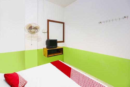 ein Schlafzimmer mit einem Bett und einem Spiegel sowie einem TV in der Unterkunft SPOT ON 92053 Bagus Stay in Tanjung Pinang 