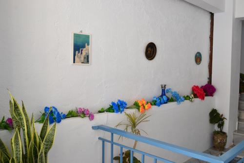 Una pared blanca con un estante azul con flores. en Manthos Holiday Home, en Agia Galini