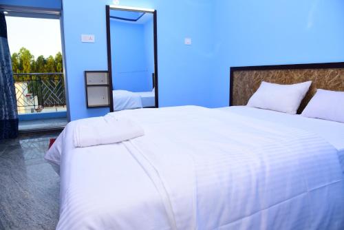 a bedroom with a large white bed with a blue wall at Thangam Residency in Kāraikkudi
