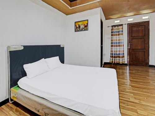 龍目島的住宿－OYO 92090 Panorama Rinjani Lodge，铺有木地板的客房内的一张白色床