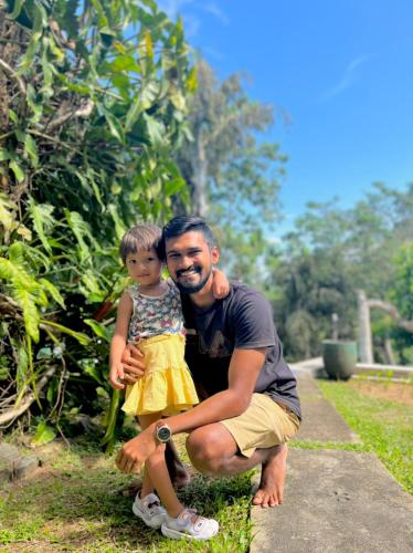 a man holding a little girl in a yellow dress at Green Hill Paradise Villa in Unawatuna