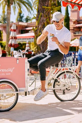 a man is riding a bike with a cart at Fairmont Grand Del Mar in San Diego