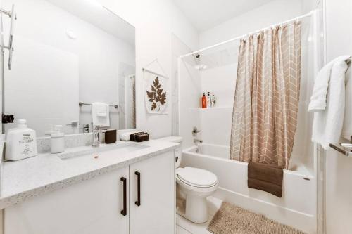 a white bathroom with a toilet and a shower at Modern Nordic Escape, 3BR Near WEM & DT, AirCon & Fireplace, Wifi, Sleeps 6! in Edmonton