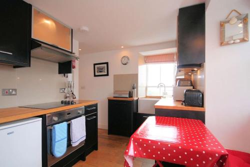 eine Küche mit einem roten Tisch in der Mitte in der Unterkunft Upper Deck, Port Isaac Bay Holidays in Port Isaac