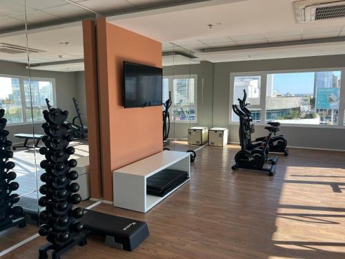 een fitnessruimte met fitnessapparatuur en een flatscreen-tv bij Blend Marista - apt 1 Qt in Goiânia