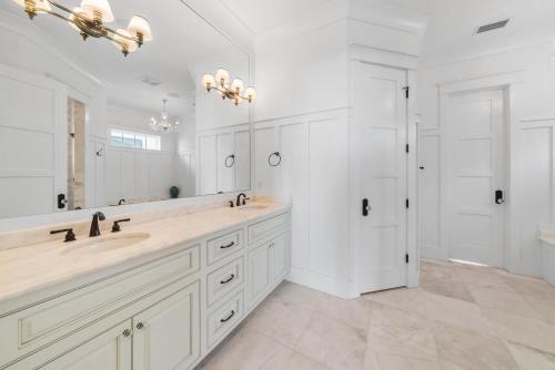 La salle de bains blanche est pourvue de 2 lavabos et d'un grand miroir. dans l'établissement Magnolia Sands, à Destin