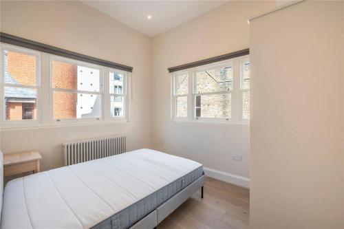a bedroom with a bed and two windows at Apartments in the heart of Richmond, London in Richmond upon Thames