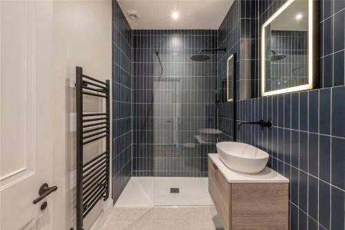 uma casa de banho com um lavatório e um chuveiro com azulejos azuis em Apartments in the heart of Richmond, London em Richmond upon Thames