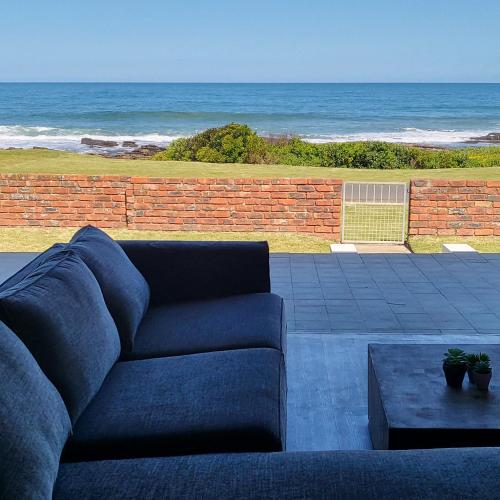 a blue couch sitting on a patio near the ocean at Villa Laks in Kiddʼs Beach