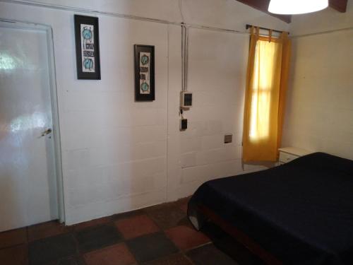Habitación con cama y puerta con cuadros en la pared. en ALOJAMIENTO SERRANO BIS en Villa Giardino