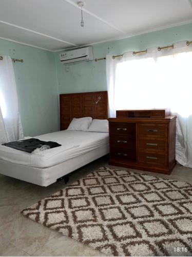 a bedroom with a bed and a dresser and a rug at Dutchlond Rooms in Freetown