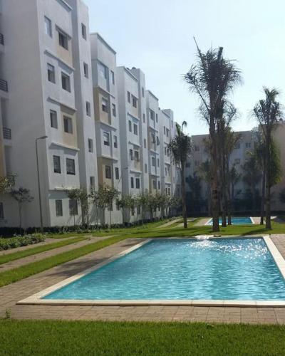 a swimming pool in front of a large building at Appartement dans résidence privée avec piscine in Tamaris