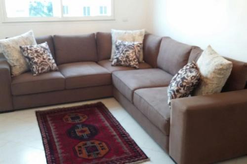 ein braunes Sofa mit Kissen im Wohnzimmer in der Unterkunft Appartement dans résidence privée avec piscine in Tamaris