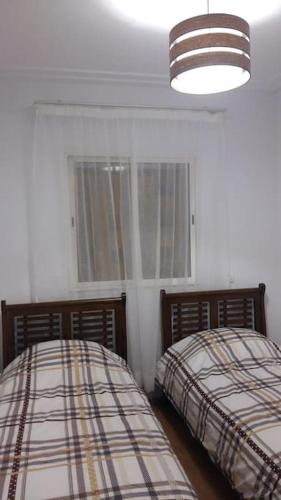 1 Schlafzimmer mit 2 Betten, einer Lampe und einem Fenster in der Unterkunft Appartement dans résidence privée avec piscine in Tamaris