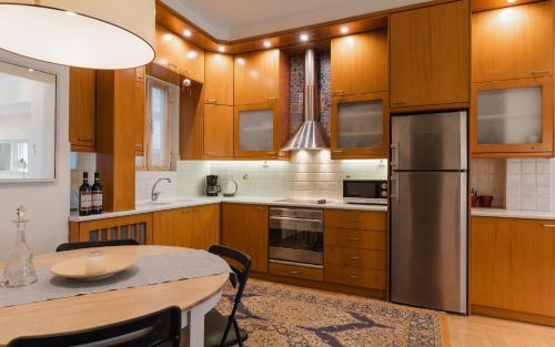 a kitchen with wooden cabinets and a table and a refrigerator at Piraeus Seaview Appartment in Piraeus