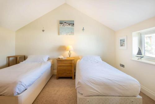 two twin beds in a room with a window at Sea Gem, Port Isaac Bay Holidays in Port Isaac