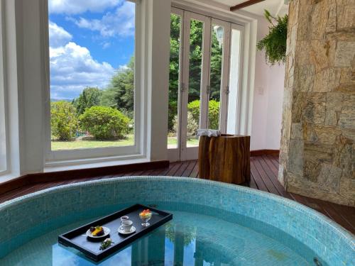 a pool with a table in a room with a window at Capivari Lodge vista incrível da natureza in Campos do Jordão