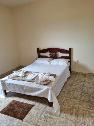 a bed with white sheets and a wooden headboard at Cantinho Silêncioso in São Thomé das Letras