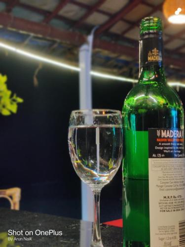 a green bottle of wine next to a glass at Happy Shack Beach And Wooden Huts in Colva