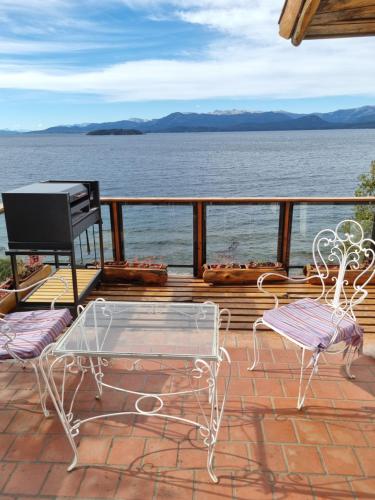 eine Terrasse mit 2 Stühlen, einem Tisch und einem Grill in der Unterkunft Melipal Schuss ARG41 in San Carlos de Bariloche