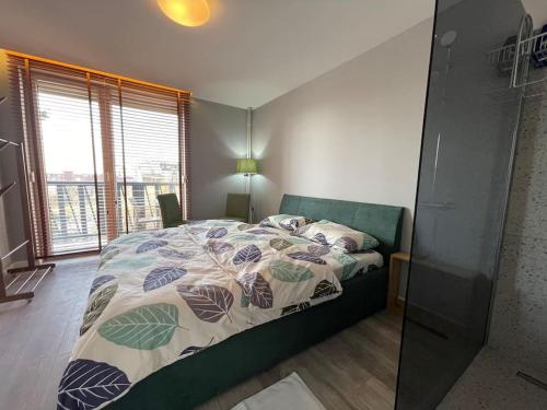 1 dormitorio con cama con edredón y ventana en Ideal Apartment n4, en Pristina